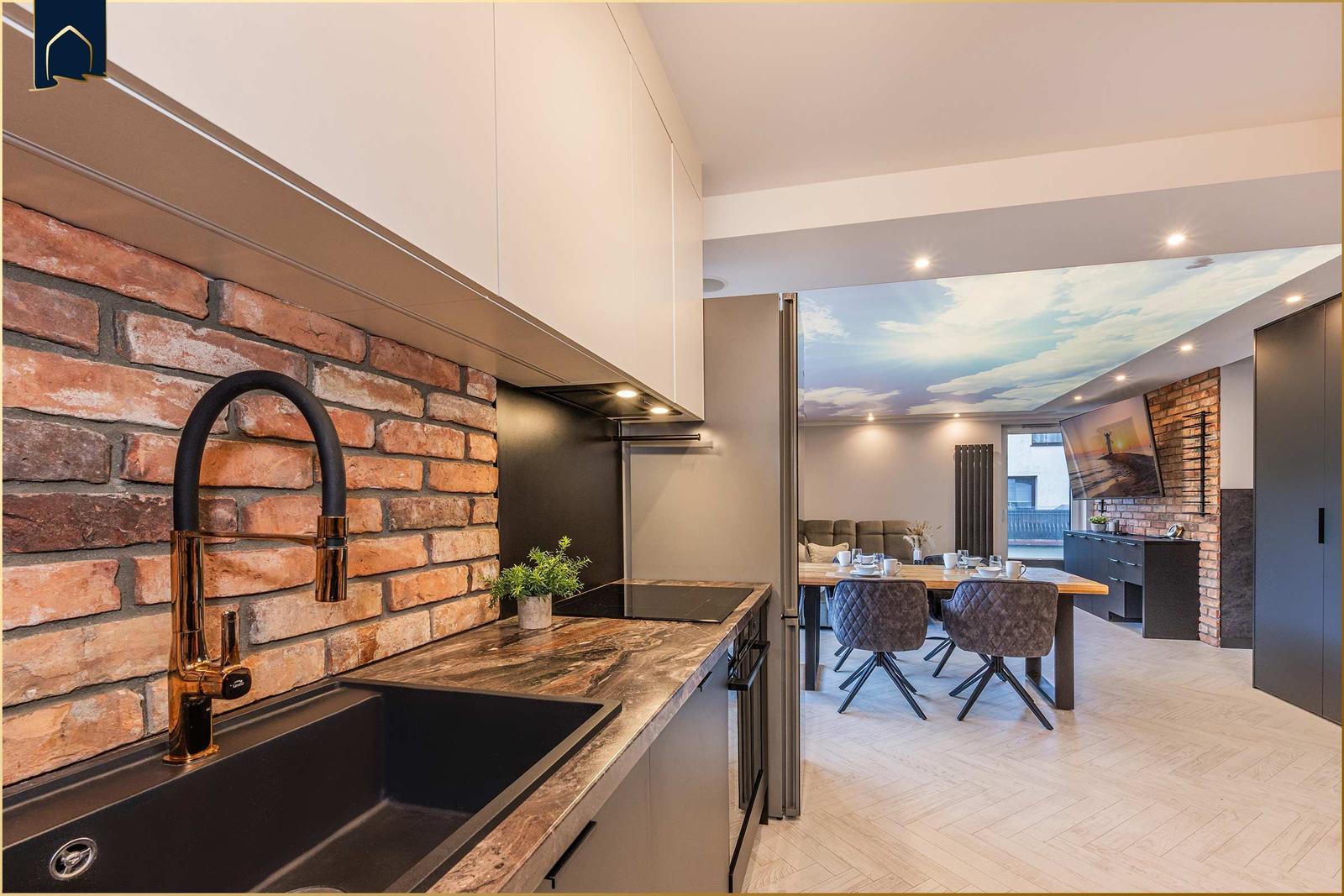 Küche mit Backsteinwand und Essbereich mit Tisch und Stühlen.