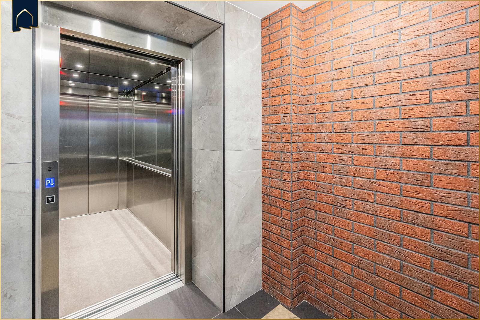 Aufnahme des Aufzugs mit Edelstahl und rotem Ziegelwand