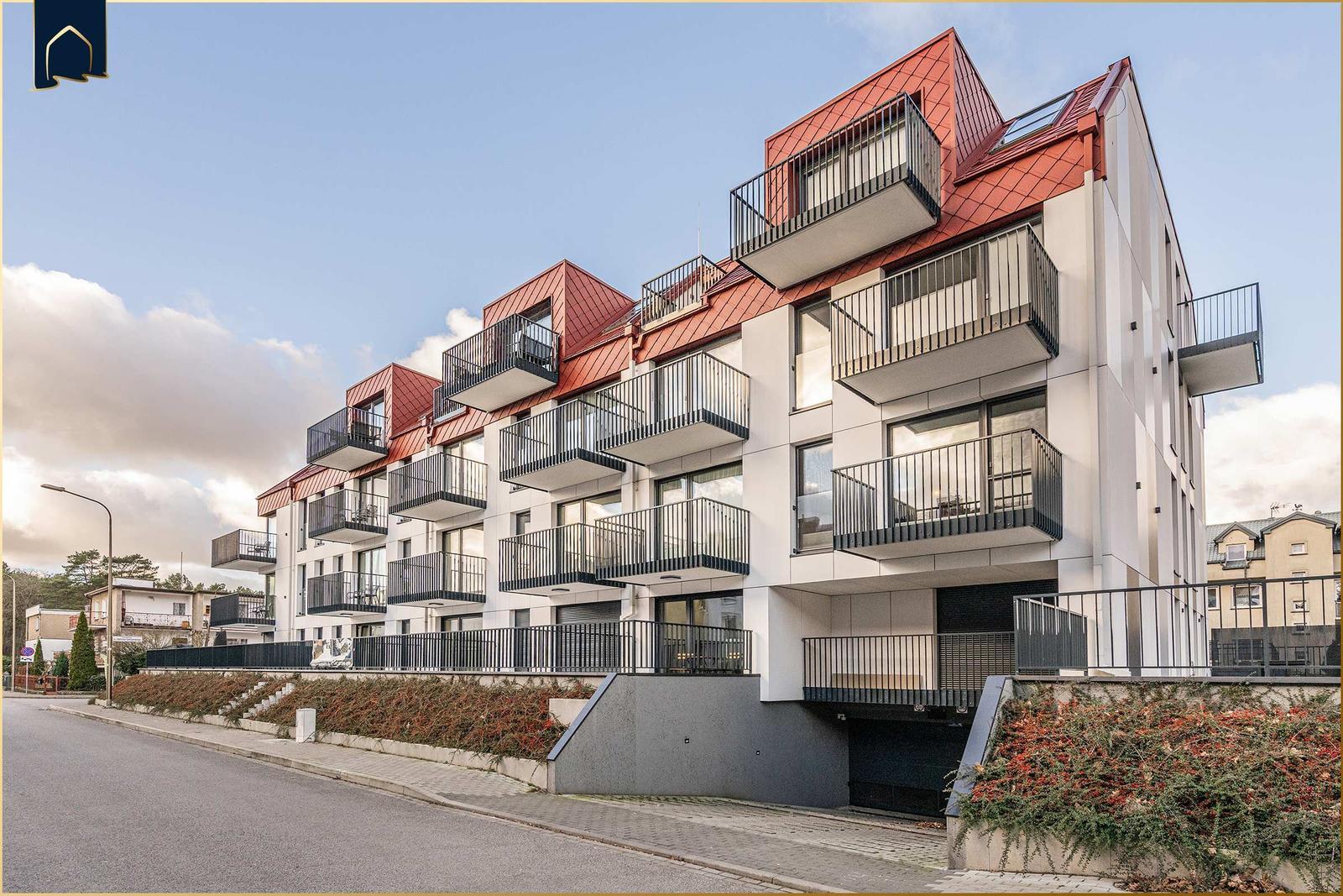 Moderne Wohnung mit Balkon und rotem Dach in ruhiger Wohngegend.