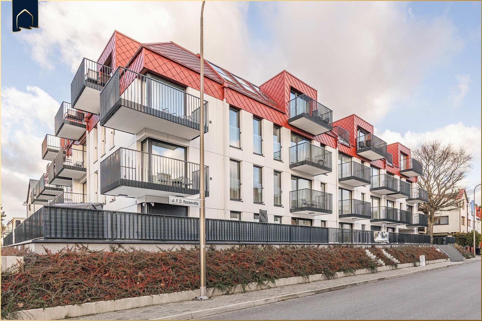 Moderne Wohnung mit Balkon und rotem Dach in ruhiger Straße.