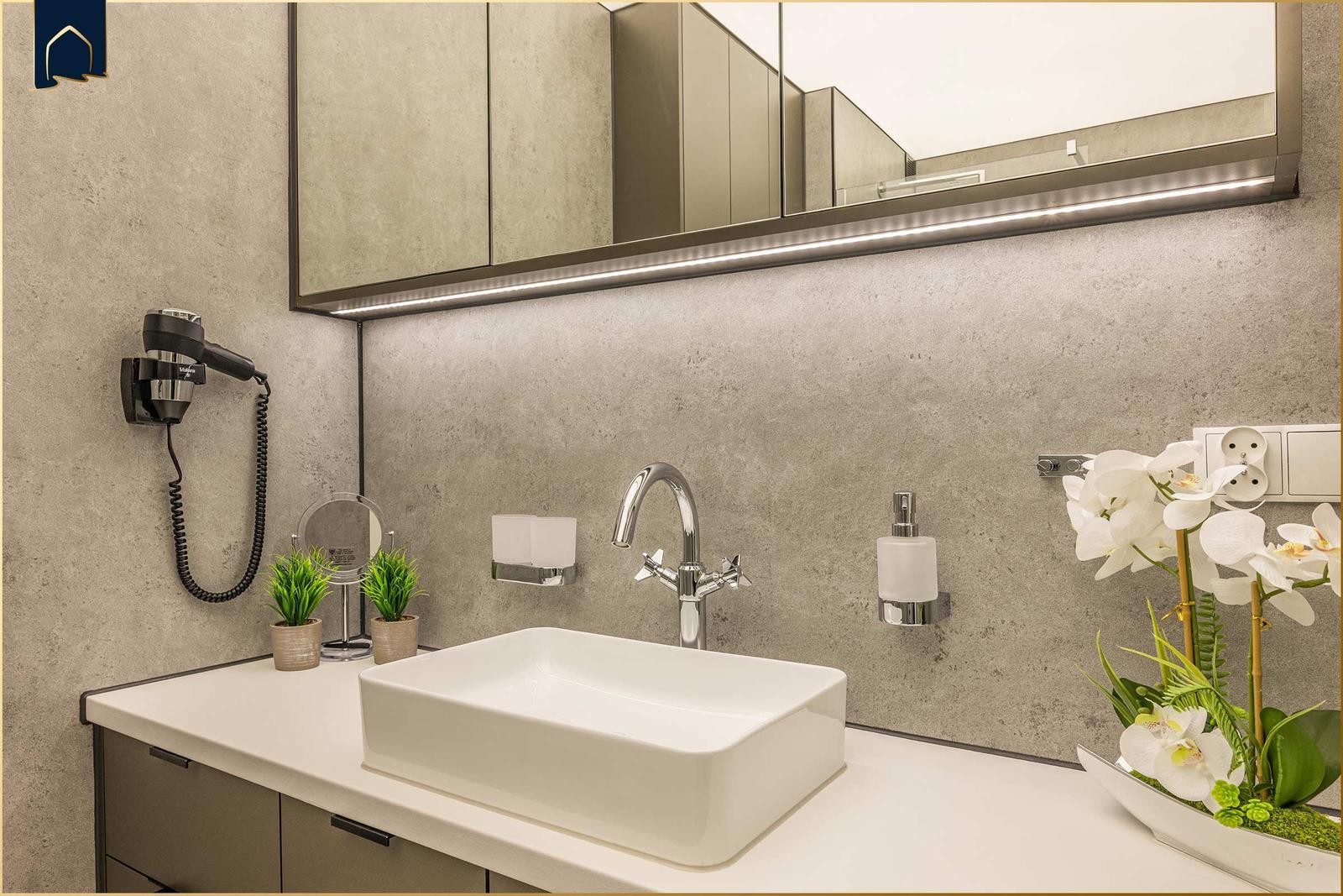 Bad mit Waschbecken, Spiegel und Haartrockner.