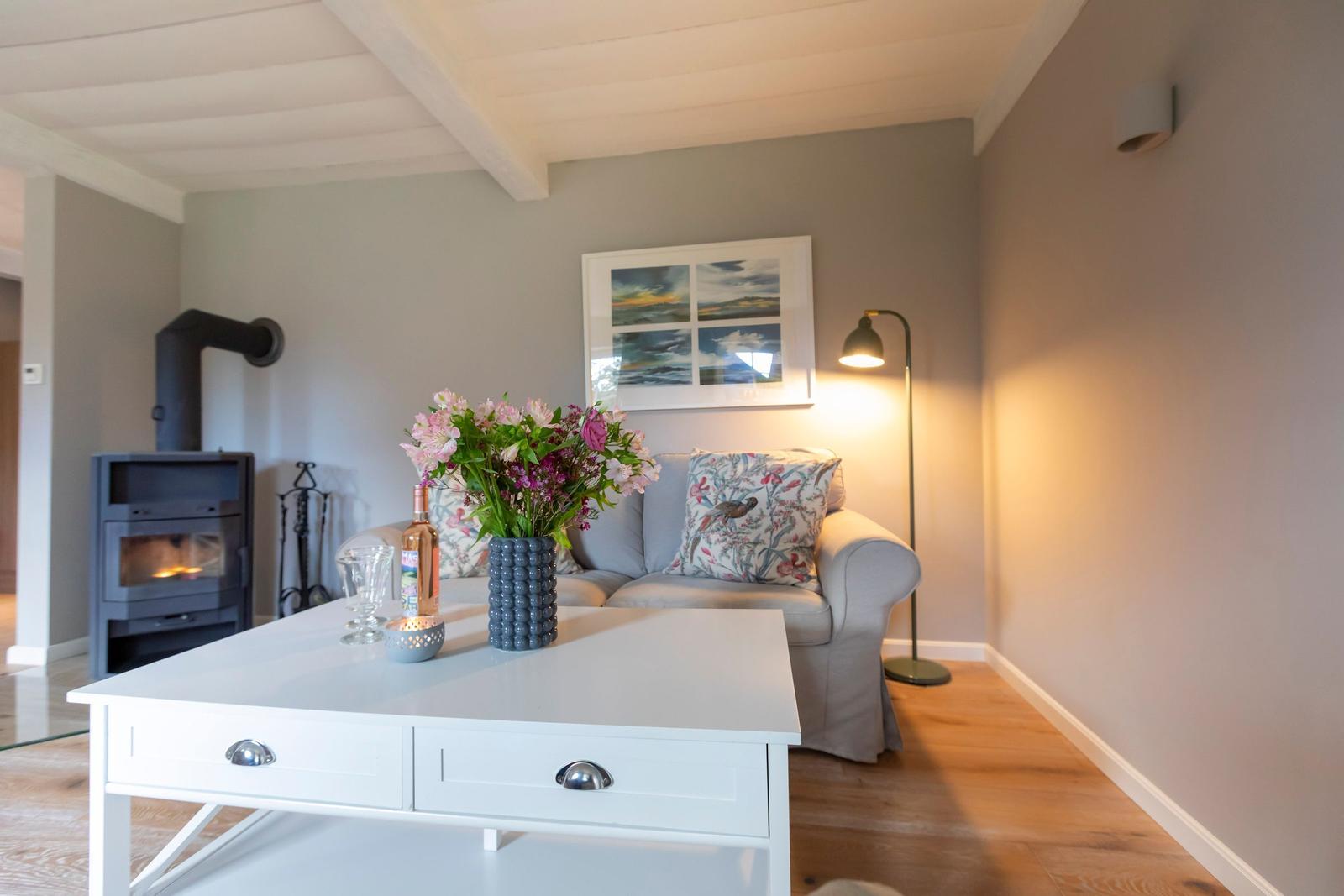 Ein Wohnzimmer mit Sofa, Tisch, Kamin und Wandbild.