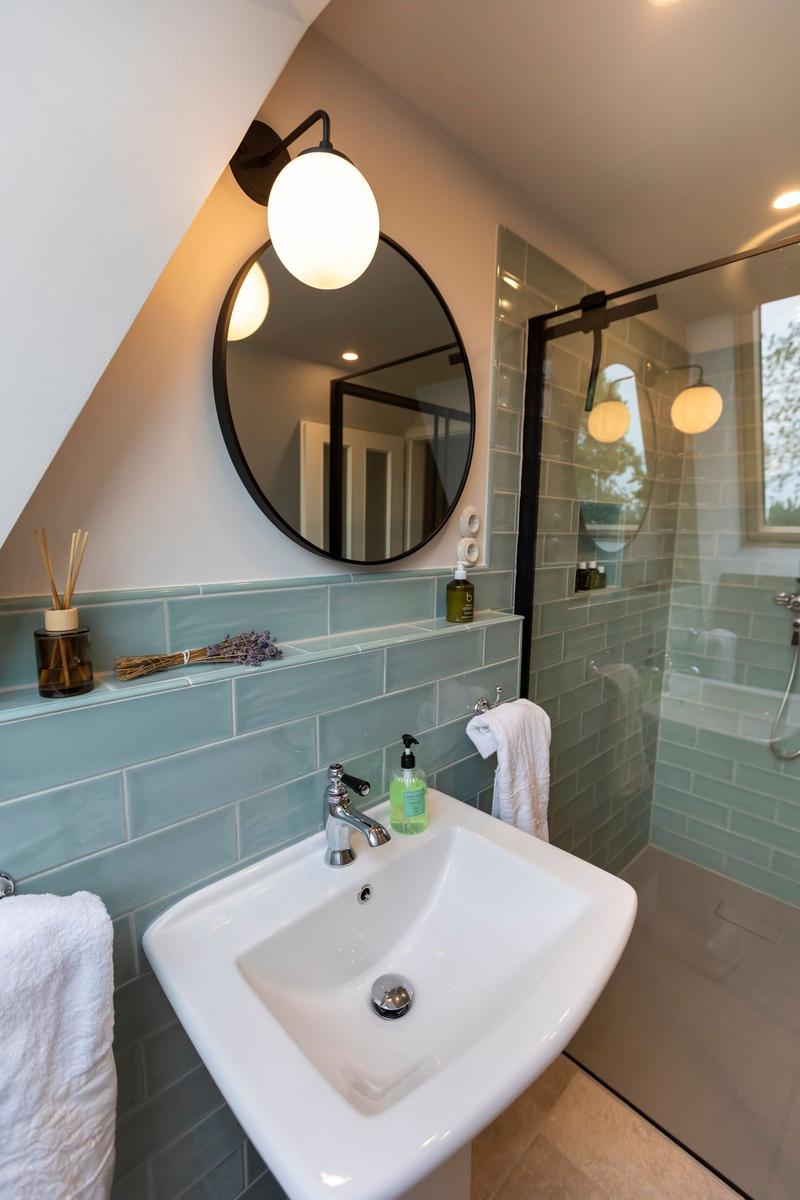 Badezimmer mit Waschbecken, Spiegel und Dusche mit Glaswand.