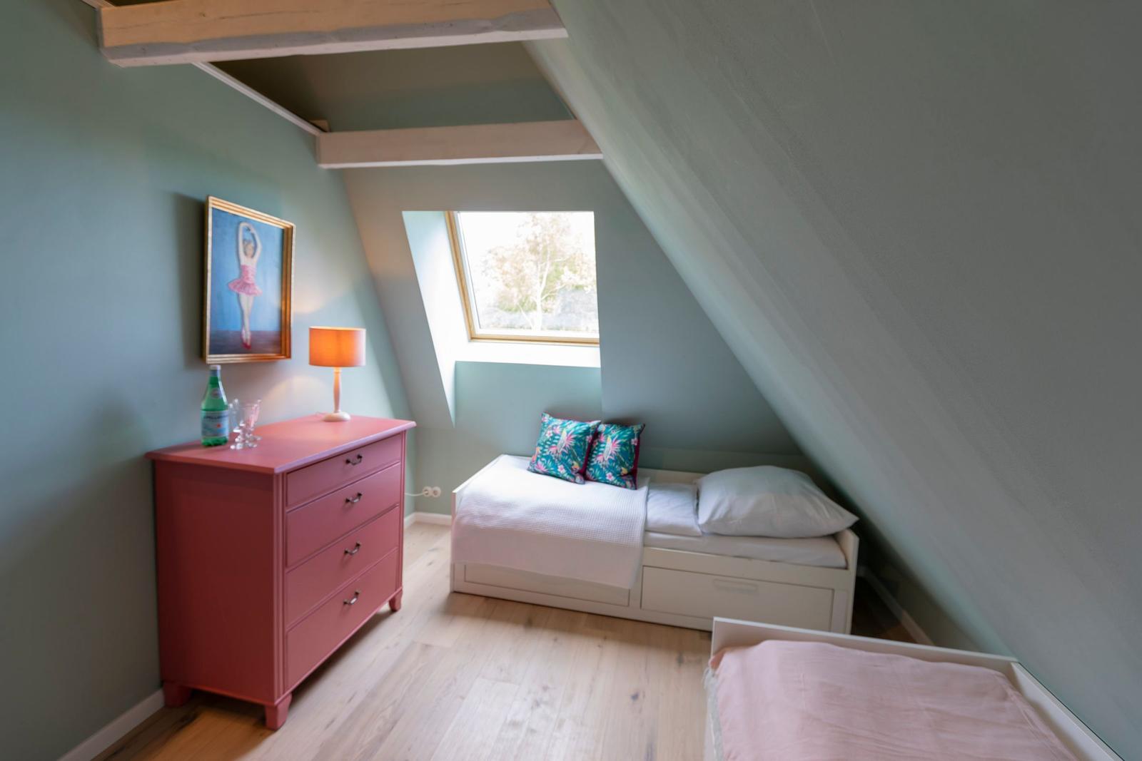 Schlafzimmer mit Dachschrägen, Fenster, Bett und Schrank.