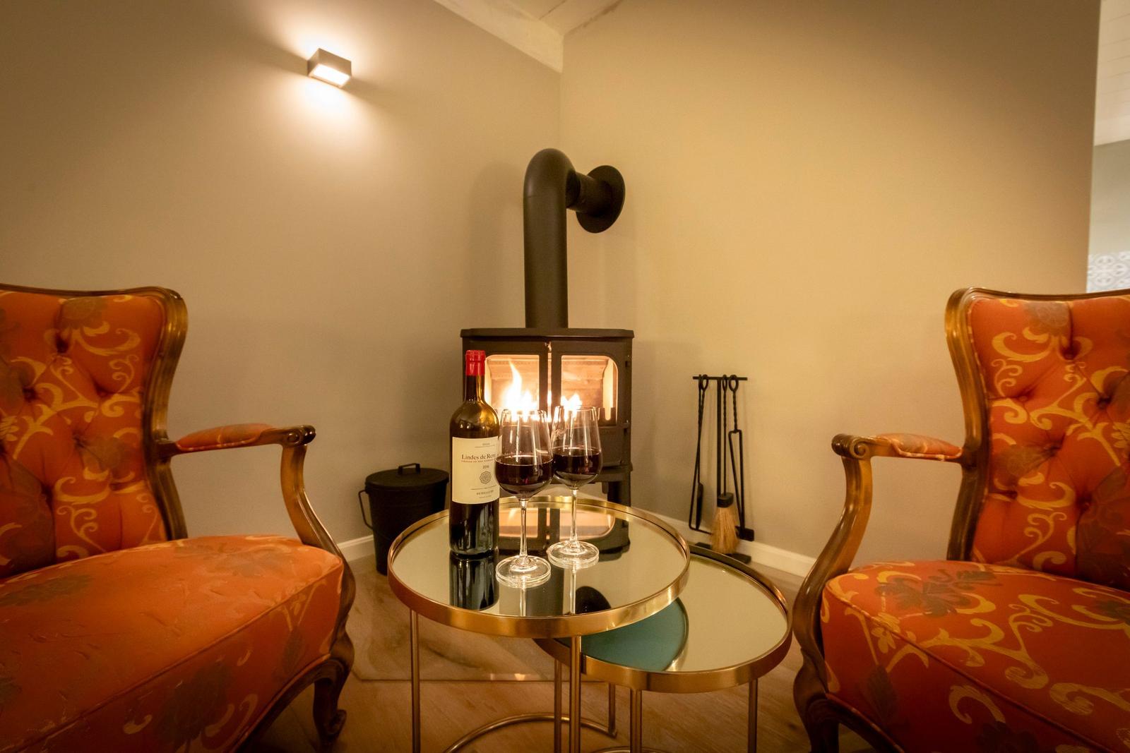 Zwei Sessel um einen Tisch mit Wein und Kamin.