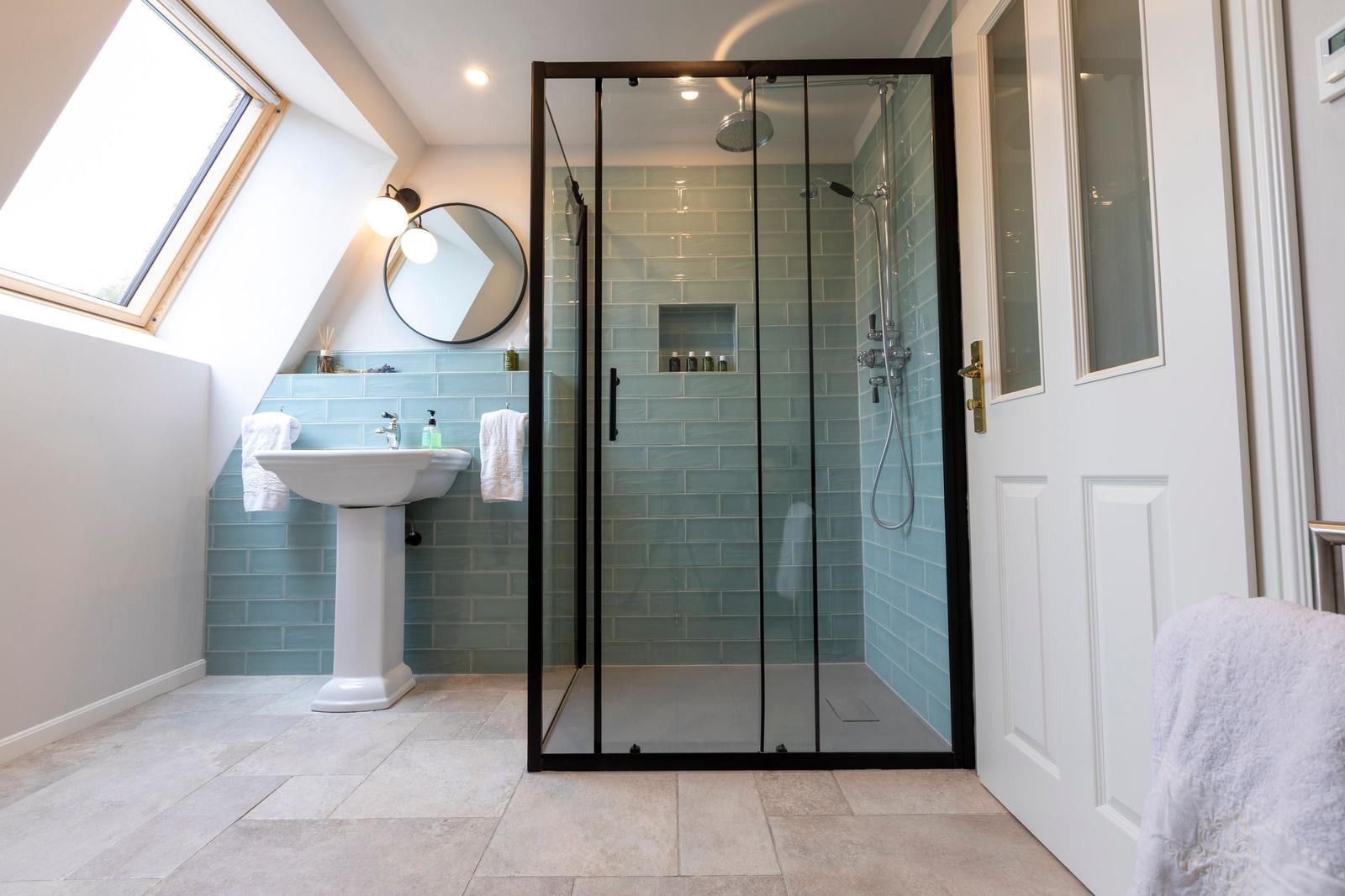 Dusche mit Glaswand, Waschbecken und Dachfenster in einem Badezimmer