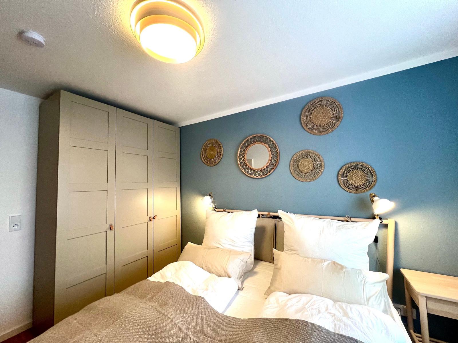 Schlafzimmer mit Bett, Kleiderschrank und Wanddekoration.