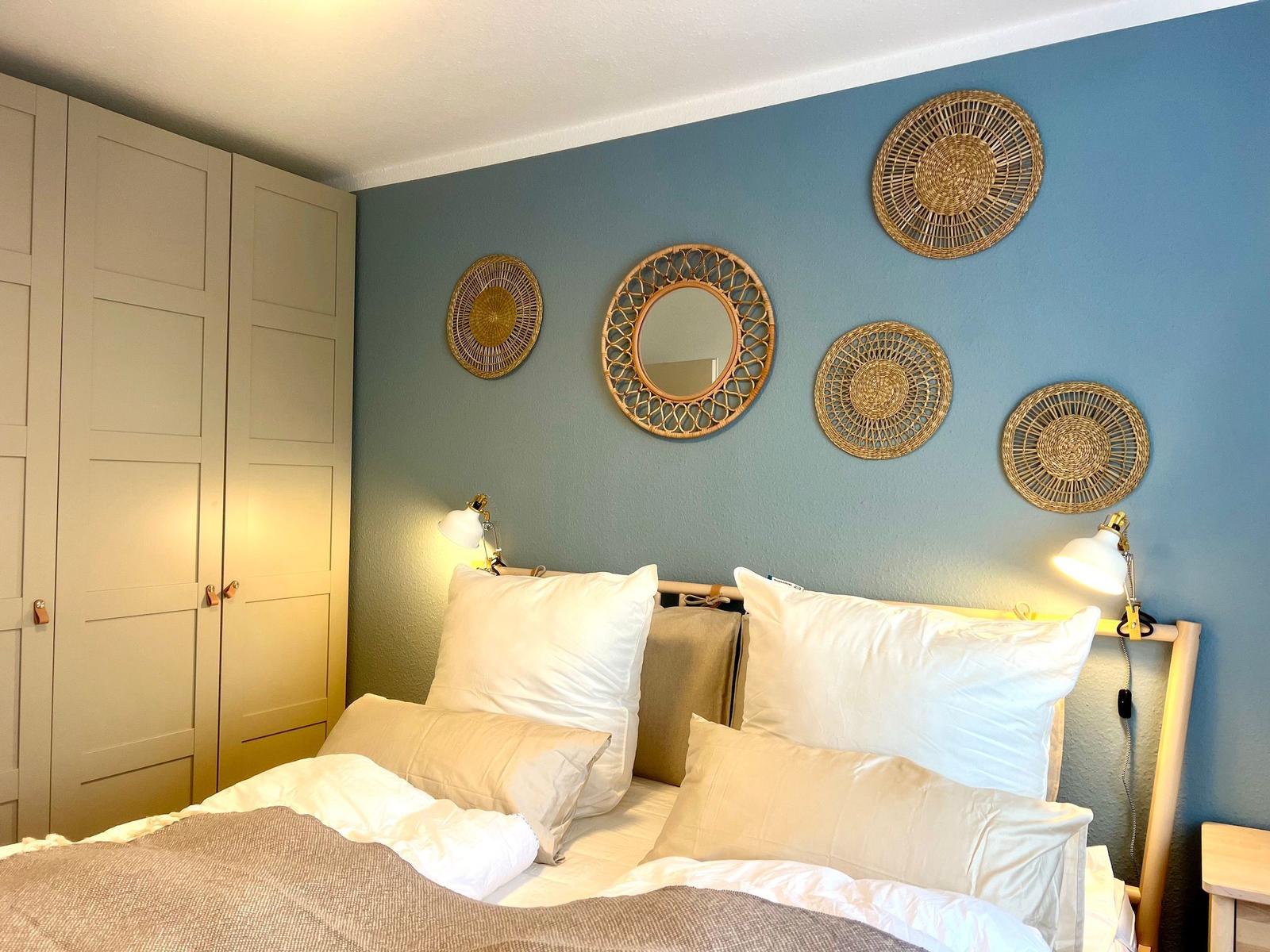 Schlafzimmer mit Bett, Kleiderschrank und Wanddekoration aus Rattan.