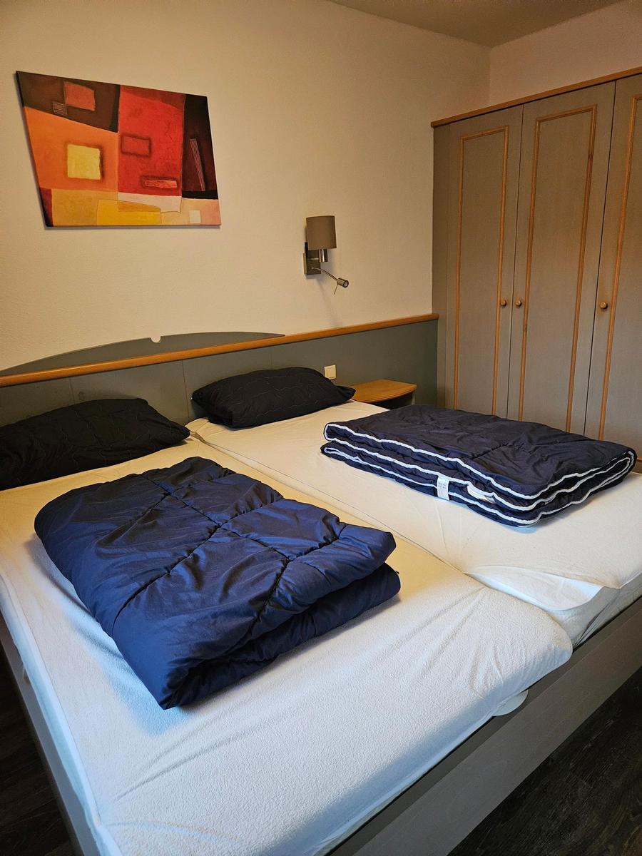 Zwei Betten mit blauen Decken, Wandbild und Kleiderschrank im Schlafzimmer.