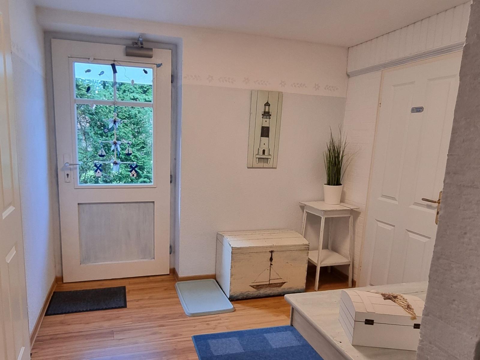 Entrance area with door, wooden floor, and nautical decor on walls.