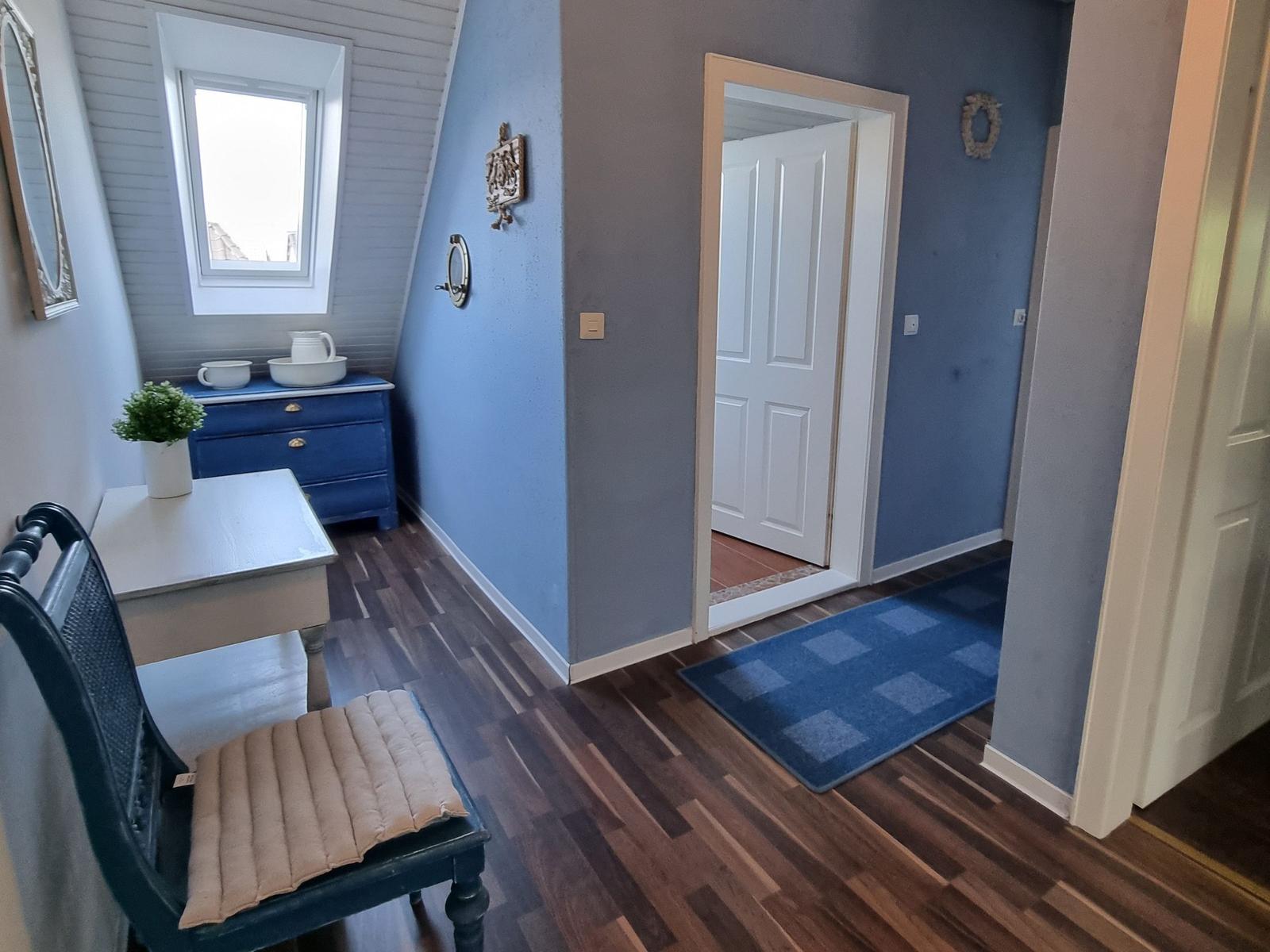 Entryway with blue walls, wooden floor, and door to hallway.