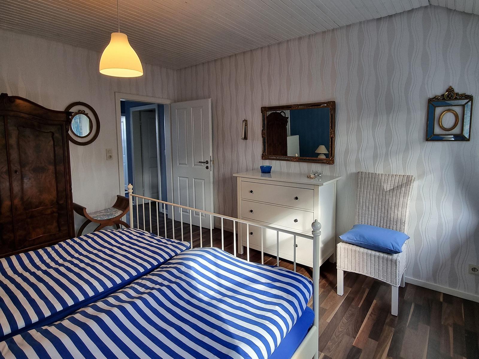 Bedroom with bed, wardrobe, mirror, and chair.