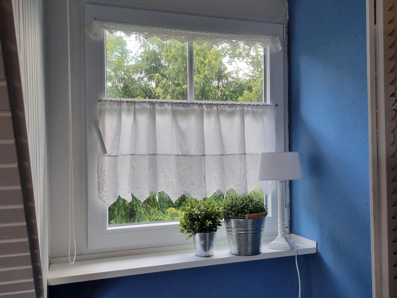 Window with white curtains and plants in metal buckets on the sill.