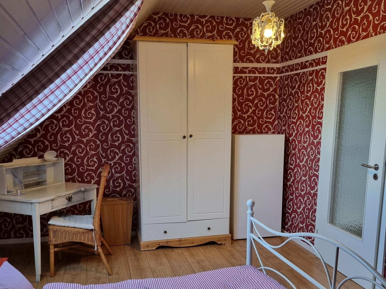 Bedroom with sloped ceiling, wardrobe, desk, and bed