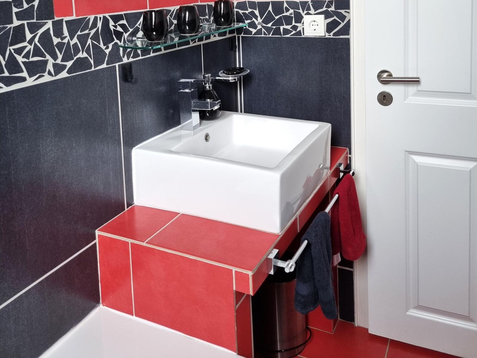 Bathroom with sink on red base, dark blue walls, and mosaic tiles.