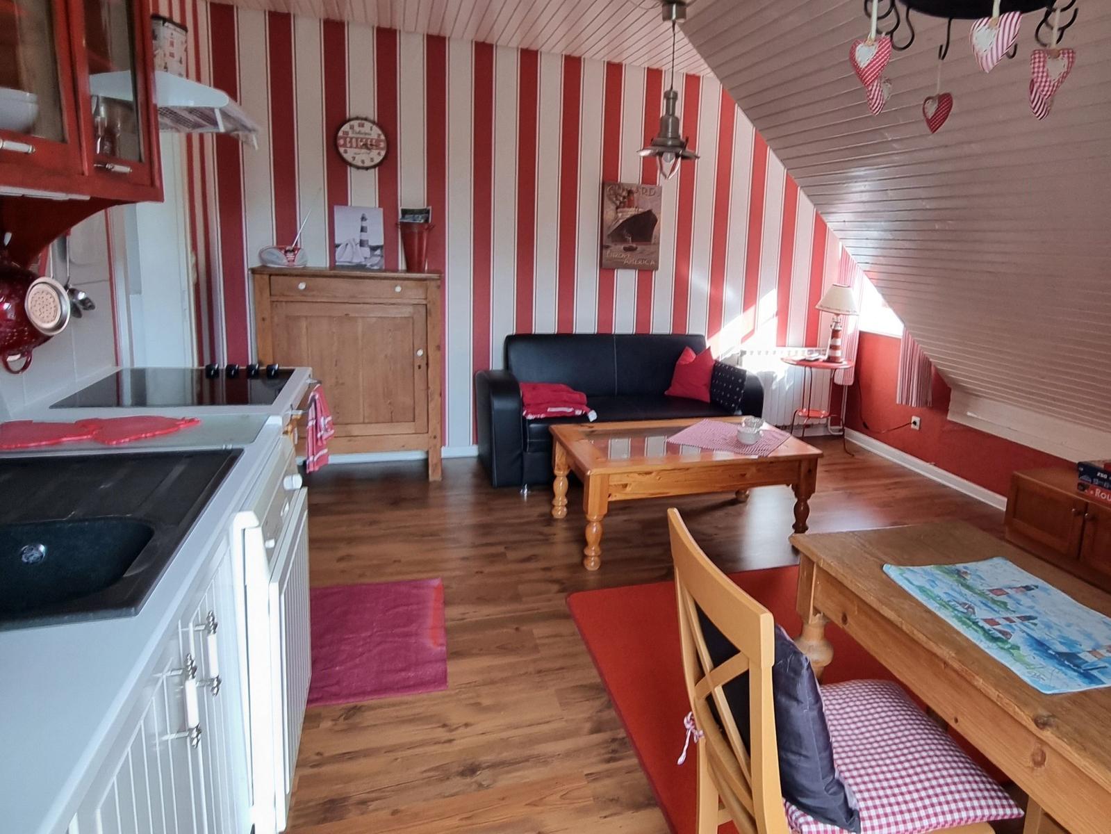 Kitchen, living, and dining area with red striped walls and wooden furniture.