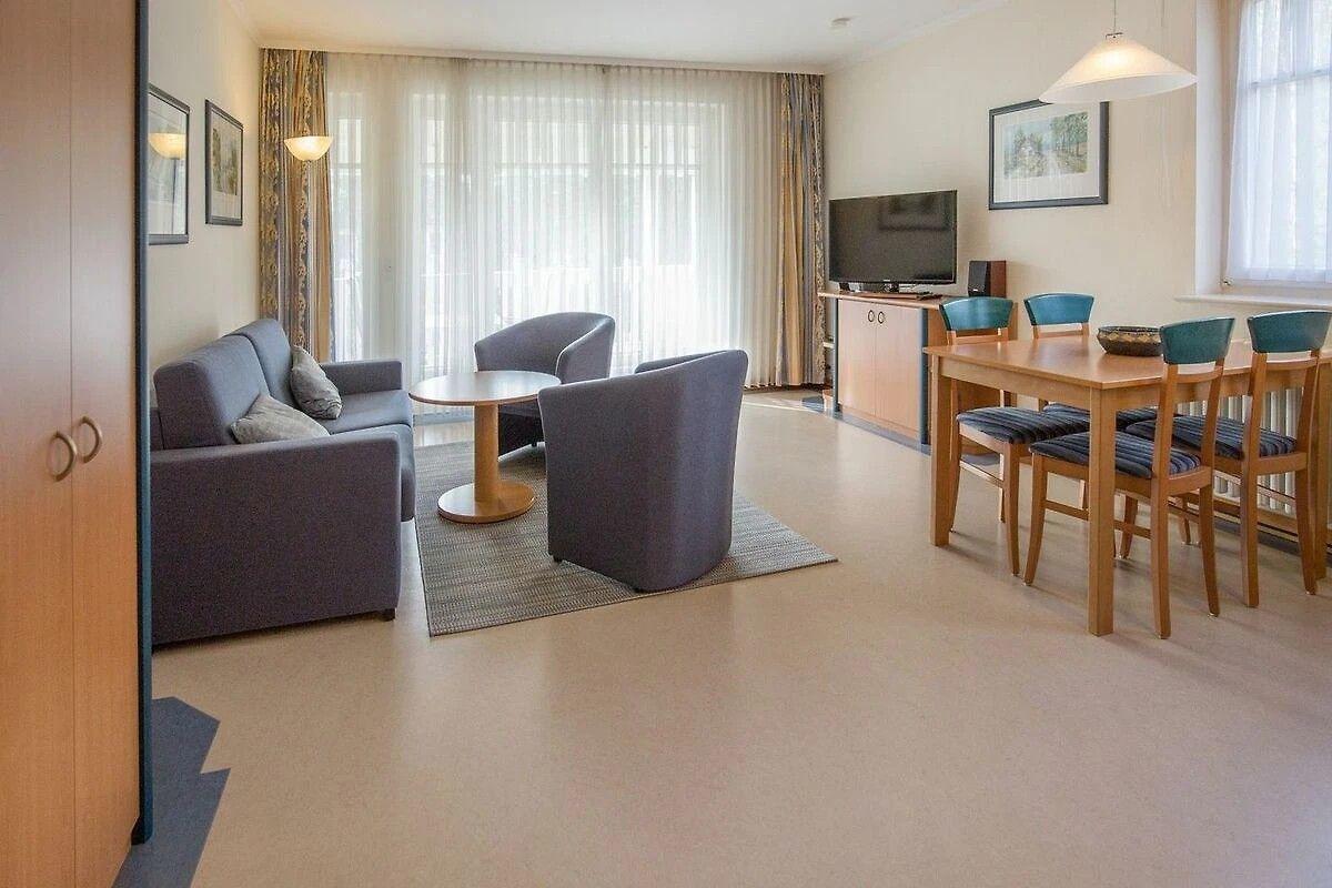 Wohn- und Essbereich mit Sofa, Stühlen und TV. Holztisch mit Stühlen.