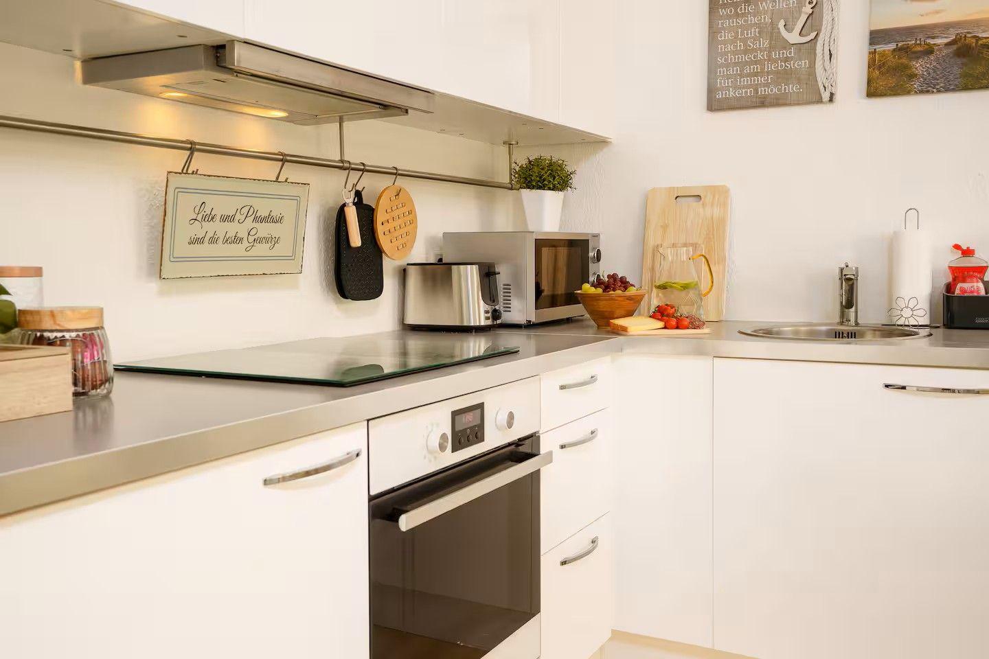 Küche mit Edelstahlarbeitsplatte, Backofen, Mikrowelle und Spüle.