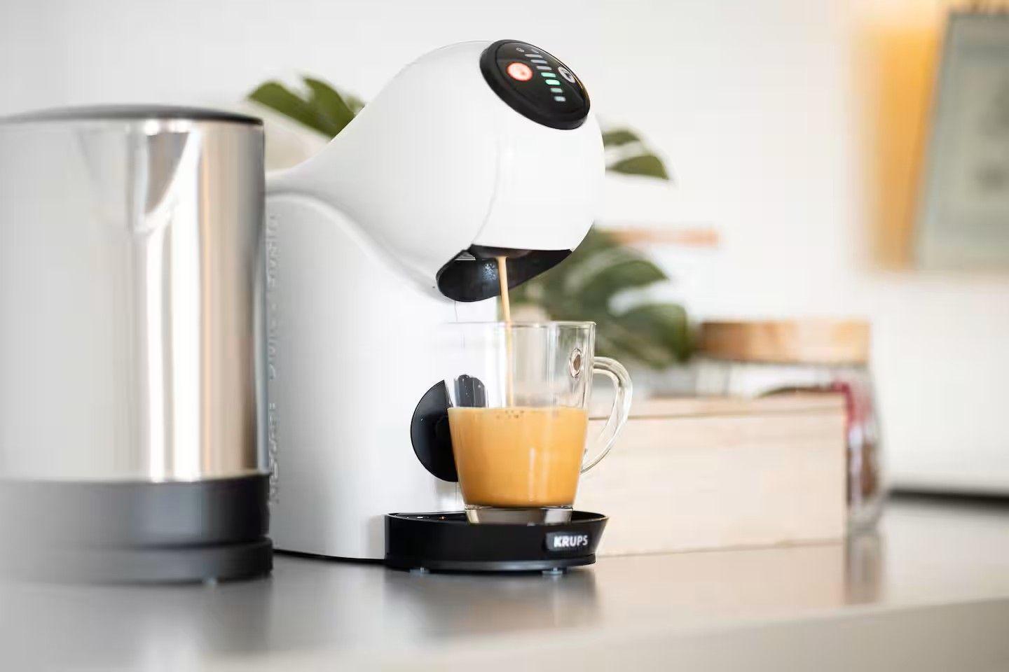 Eine Kaffeemaschine gießt Kaffee in ein Glas auf einer Arbeitsfläche.