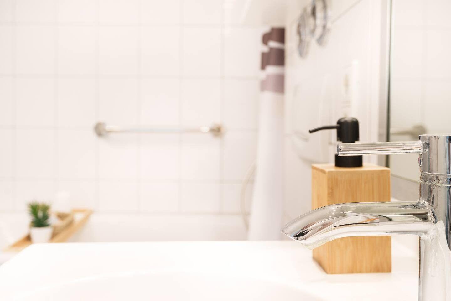 Bad mit Waschbecken, Dusche und Handtuchhalter.