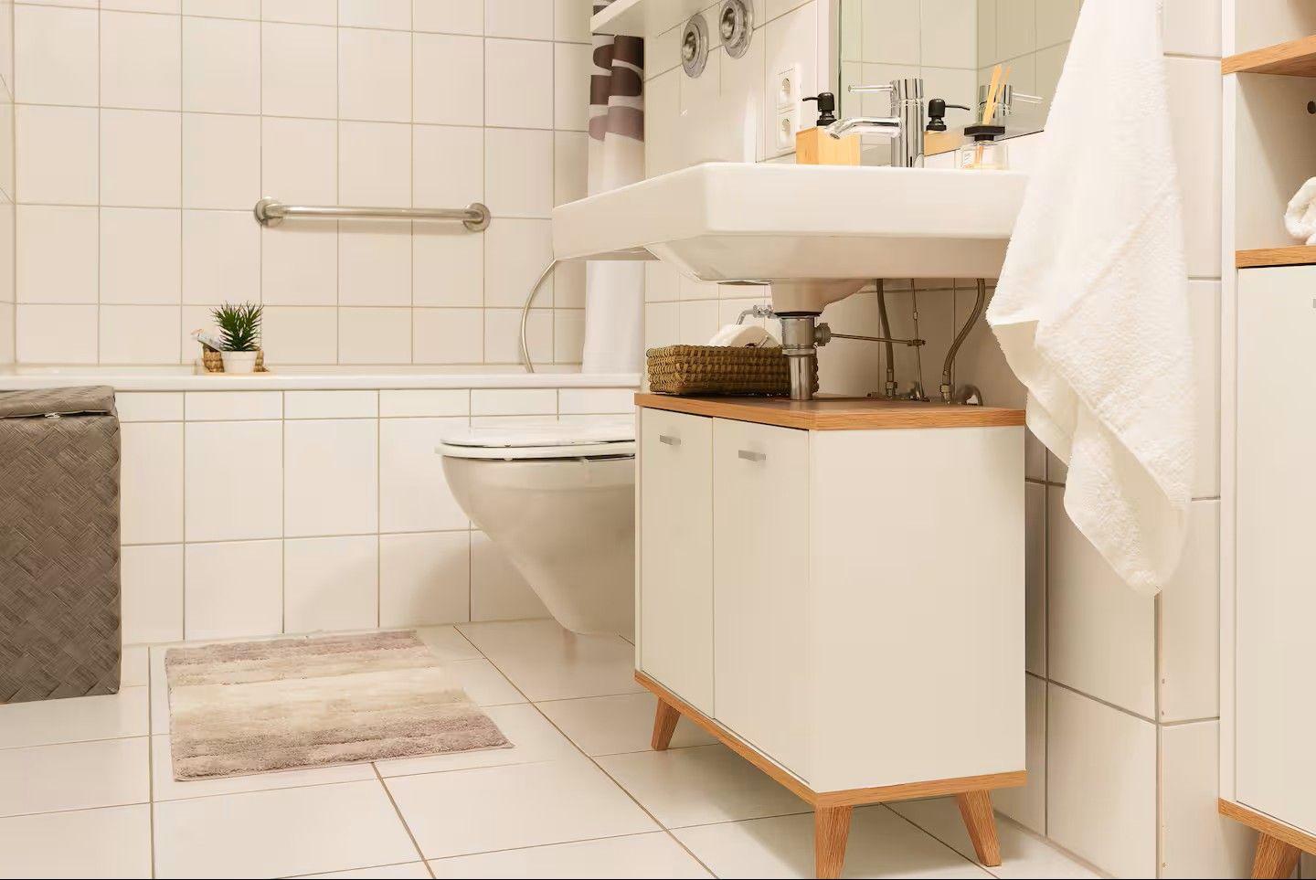 Badezimmer mit Waschbecken, Toilette und Badewanne. Holzoberfläche und Handtuch.