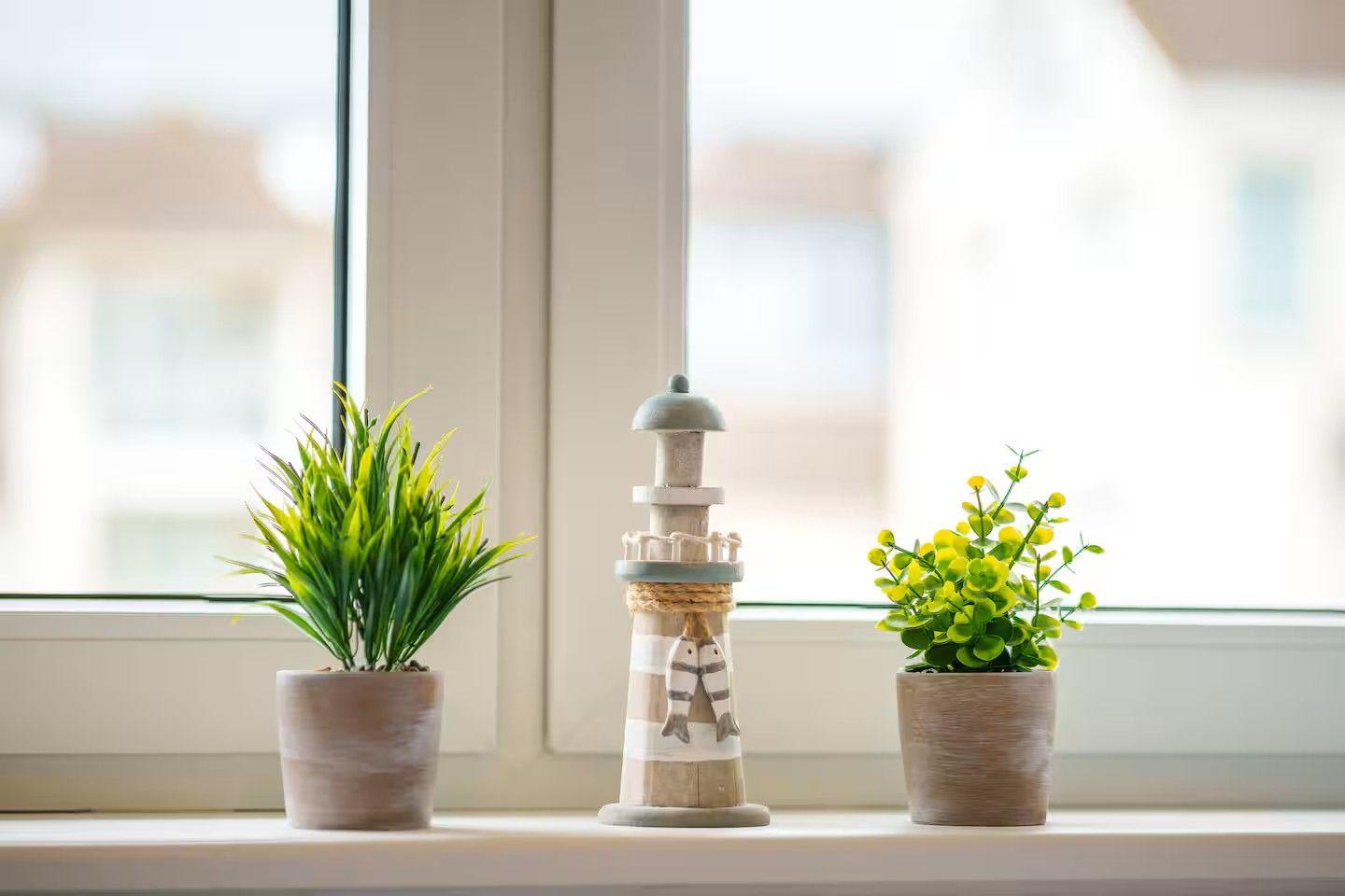 Auf dem Fensterbrett stehen zwei Pflanzen und eine Laterne.