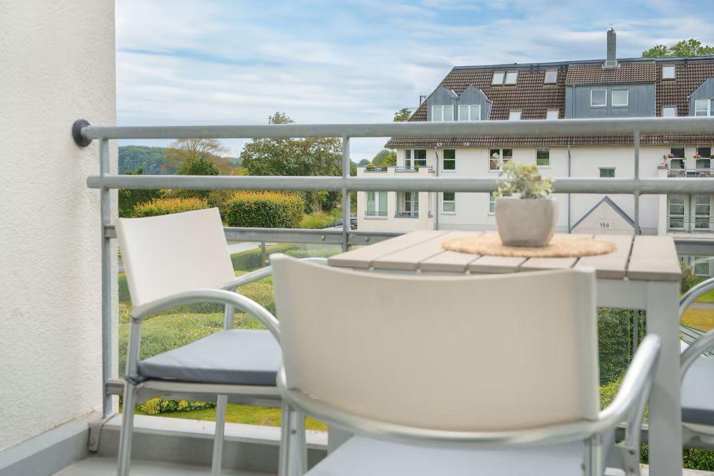 Terrasse mit Tisch und Stühlen. Blick auf Wohnhaus und grüne Landschaft.