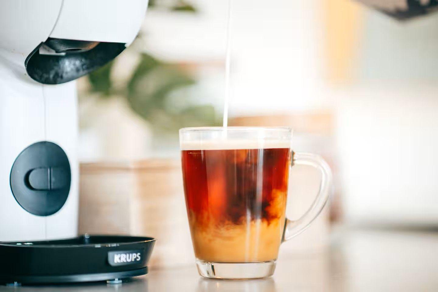 Kaffee wird in ein Glas gegossen, daneben steht eine Kaffeemaschine.