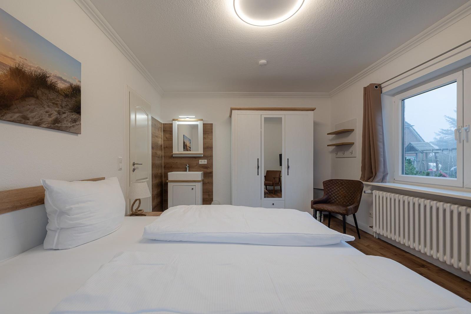 Schlafzimmer mit Bett, Kleiderschrank, Bad und Fenster.