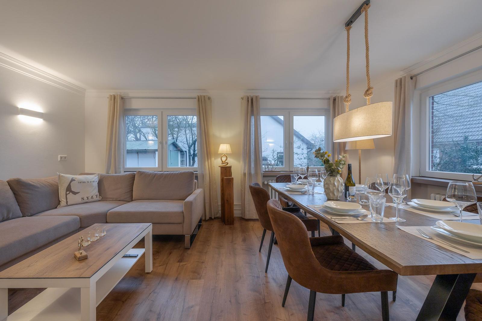 Wohn- und Essbereich mit Sofa, Esstisch und Fenstern.