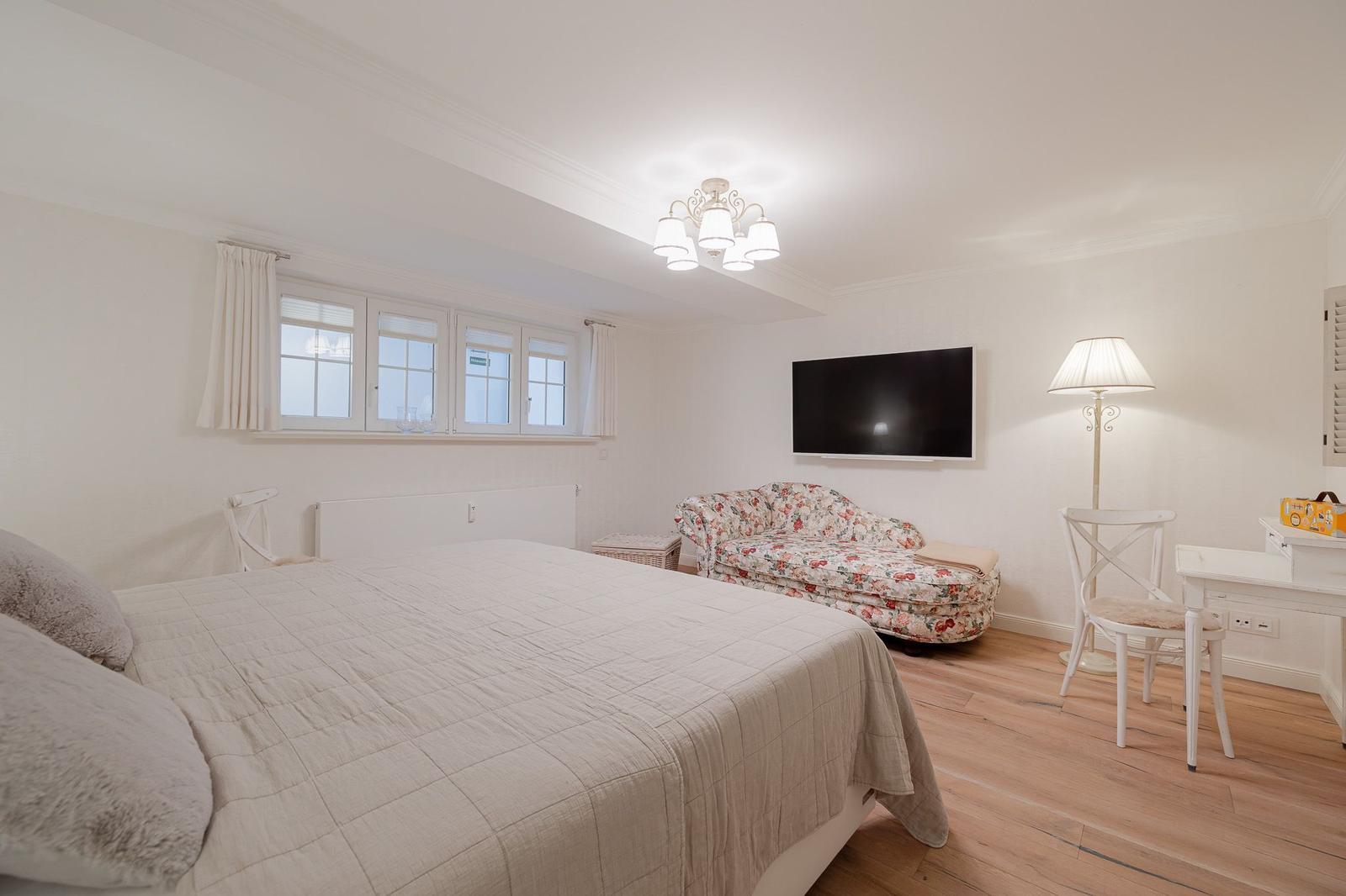 Schlafzimmer mit Bett, Sofa, TV und Schreibtisch.