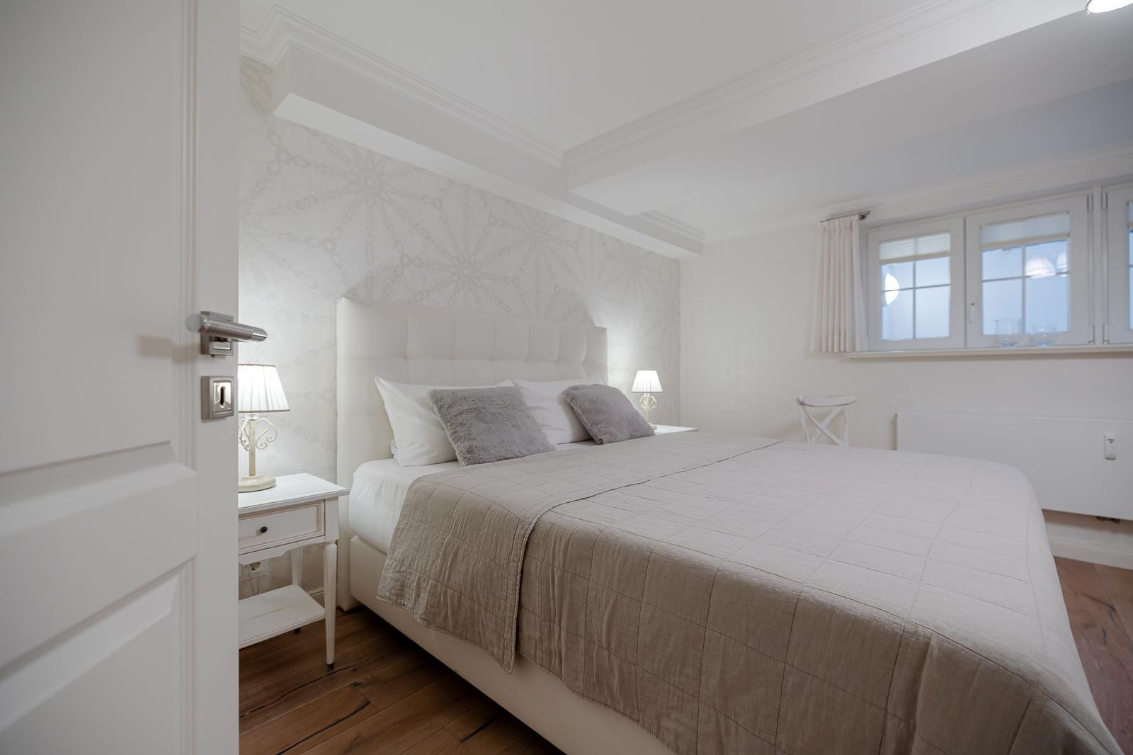 Schlafzimmer mit Bett, Nachttisch und Fenster.