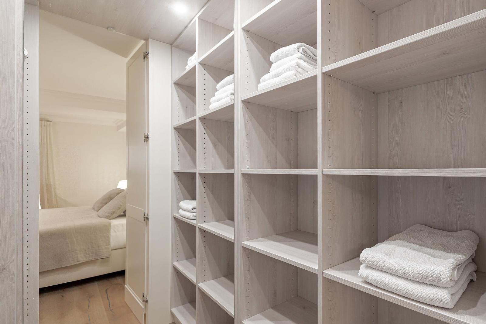 Große Garderobe mit weißen Handtüchern. Im Hintergrund ist das Schlafzimmer zu sehen.