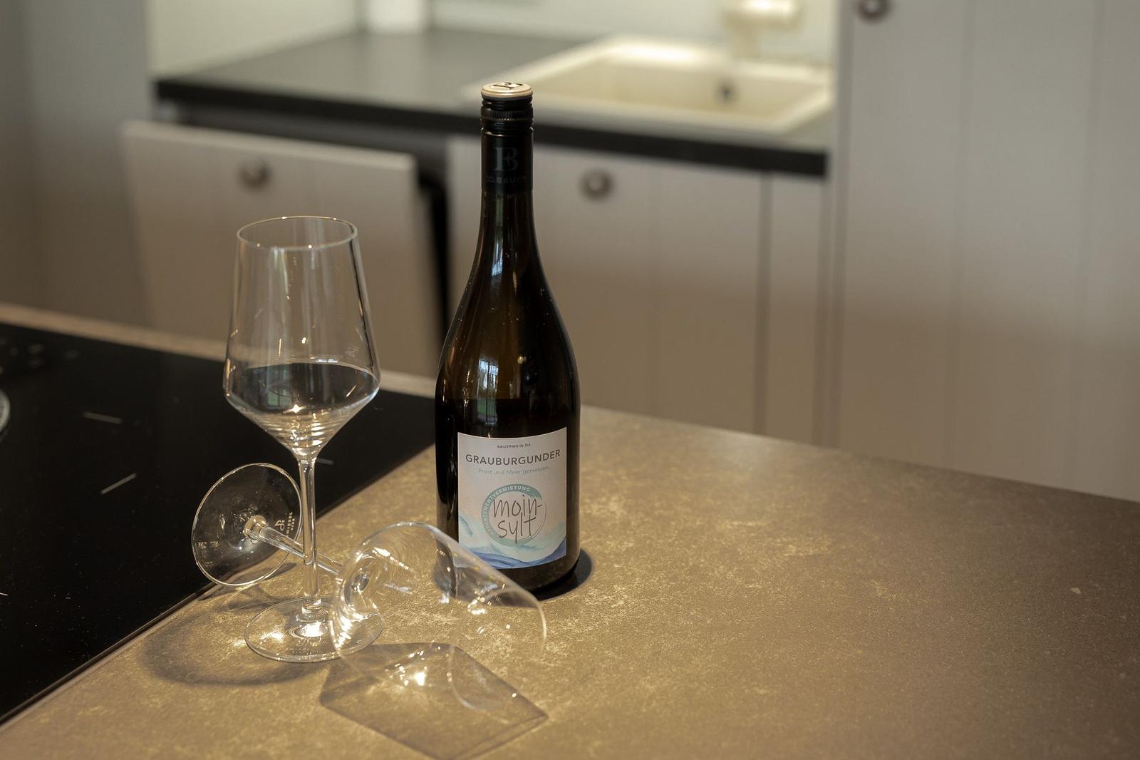 Eine Weinflasche und zwei Gläser stehen auf der Küchenarbeitsplatte.