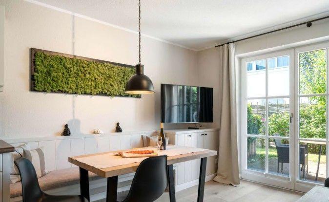 Essbereich mit Tisch, Stühlen und Fernseher. Große Glastür führt auf eine Terrasse.