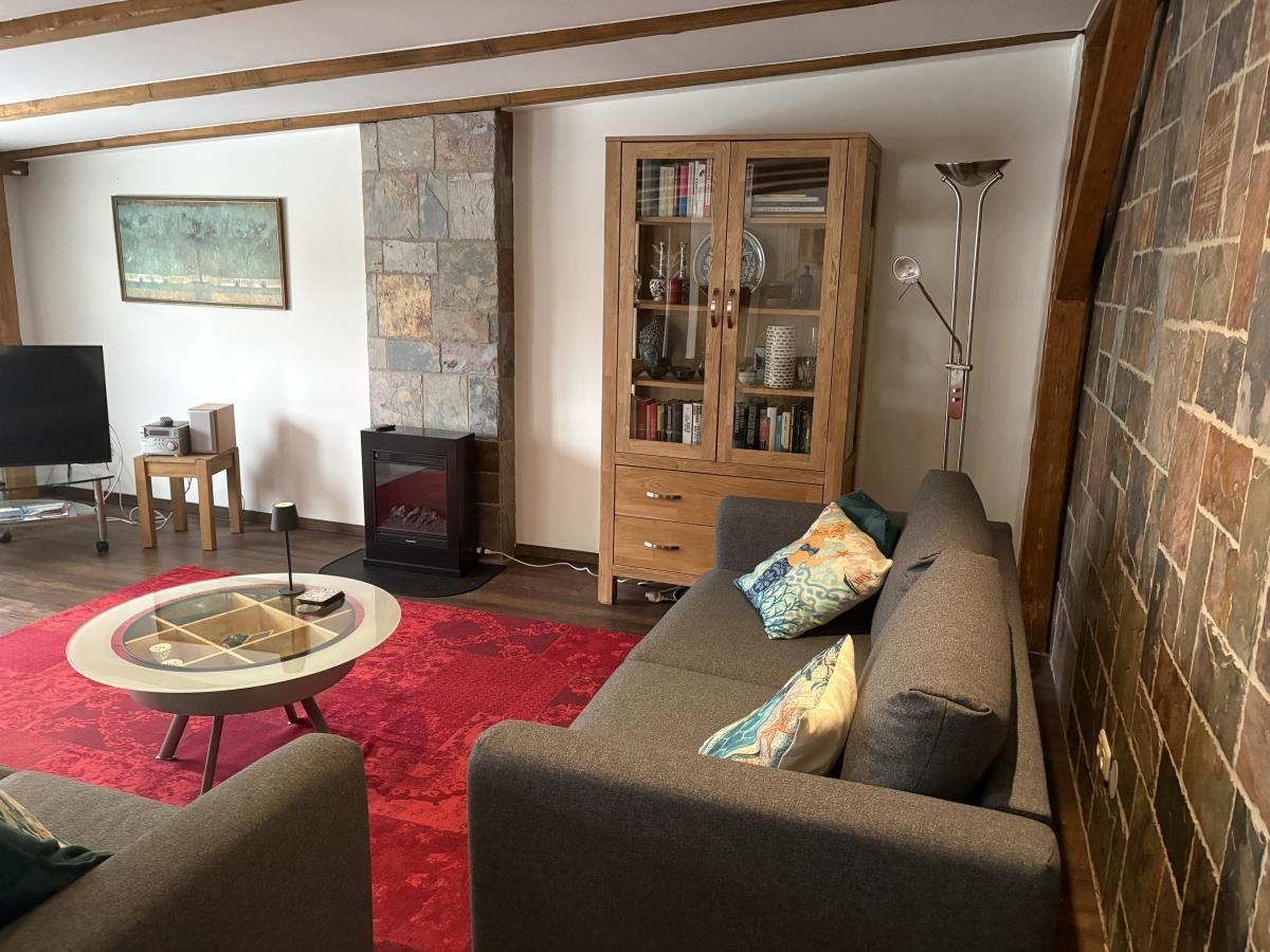 Wohnzimmer mit Sofa, Couchtisch, Bücherregal und Kamin