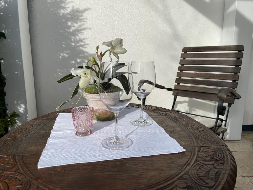 Runder Tisch mit Blumenvase, Gläsern und Stuhl im Freien.