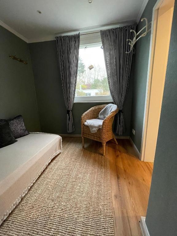 Schlafzimmer mit Bett, Stuhl und Fenster mit Vorhängen.