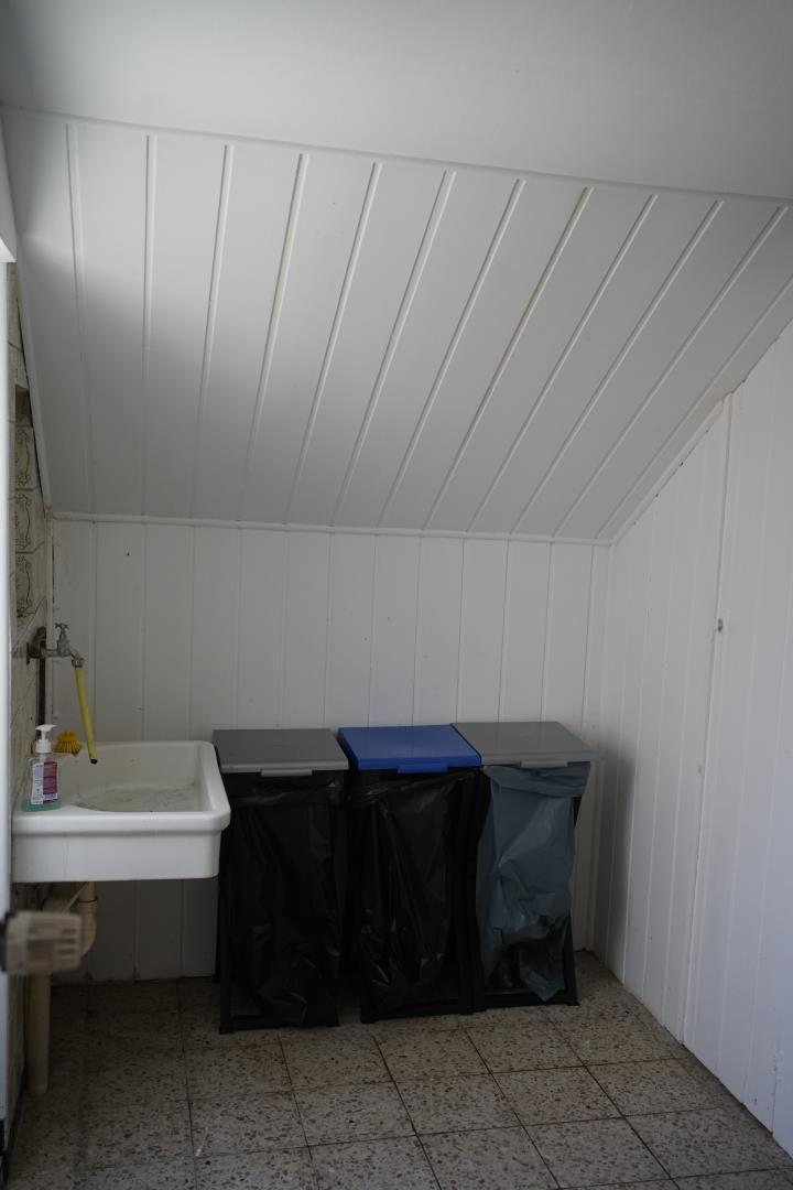 Small room with sink and three trash bins with black bags.