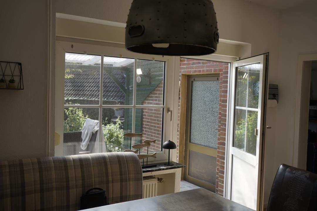 Indoor space with window and door to garden. View of a terrace and fence.