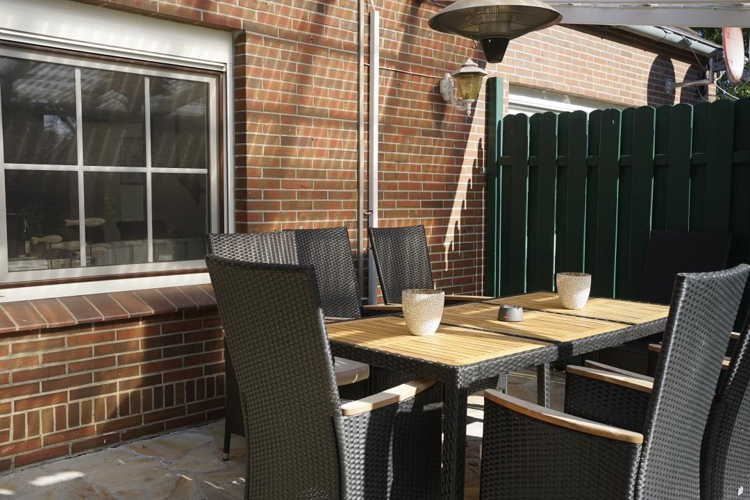 Terrace with table, chairs, and heater against brick wall