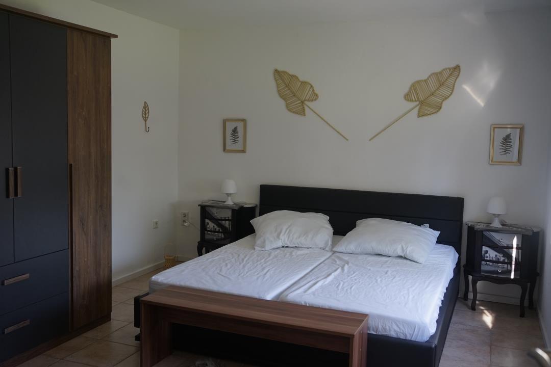 Bedroom with double bed, nightstands, and wardrobe. Wall decor with leaf motifs.
