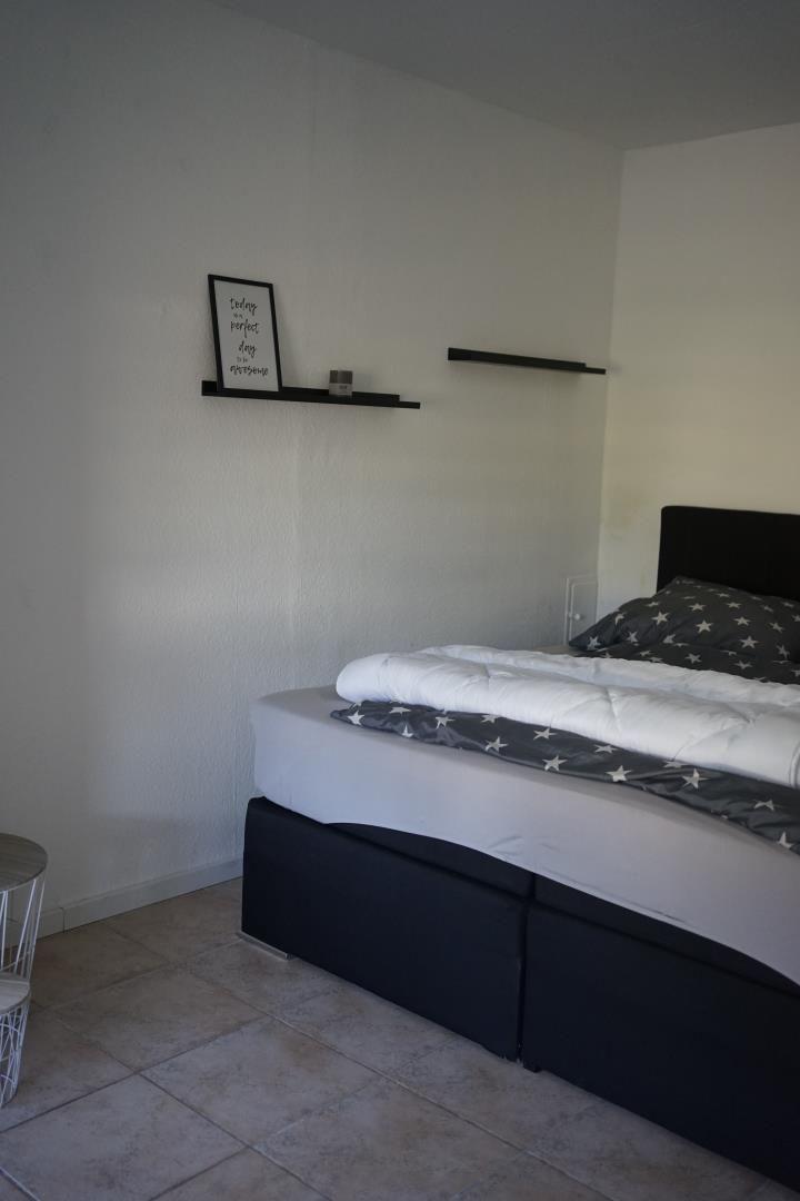 Bedroom with bed, wall shelf, and small table