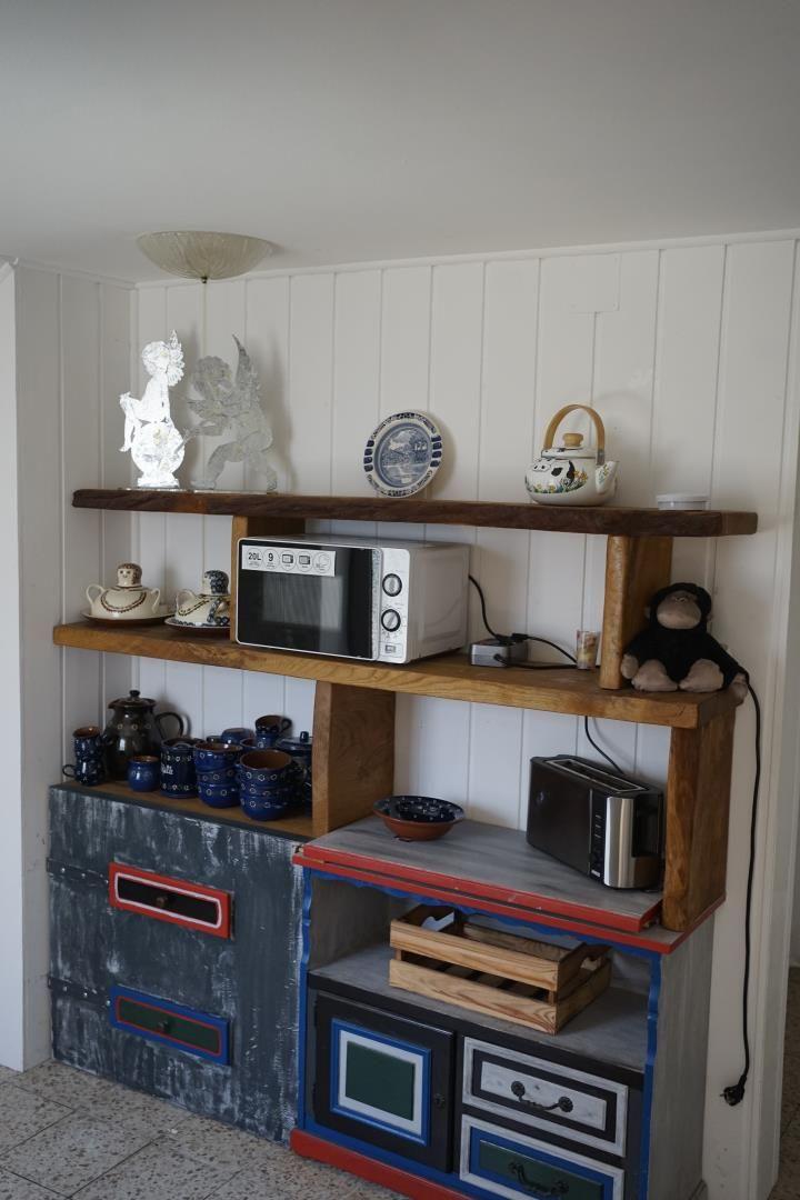 Kitchen area with microwave, toaster, and decorative items on wooden shelves.