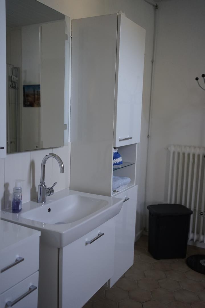 Bathroom with sink, mirror, and white cabinets