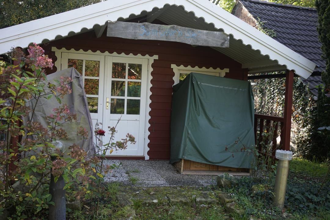 House with white doors and red walls, surrounded by plants and a green cover.