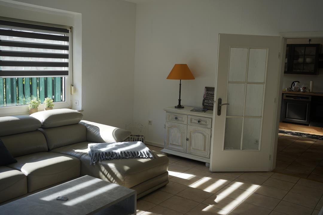 Living room with sofa, coffee table, and cabinet. Door leads to the kitchen.