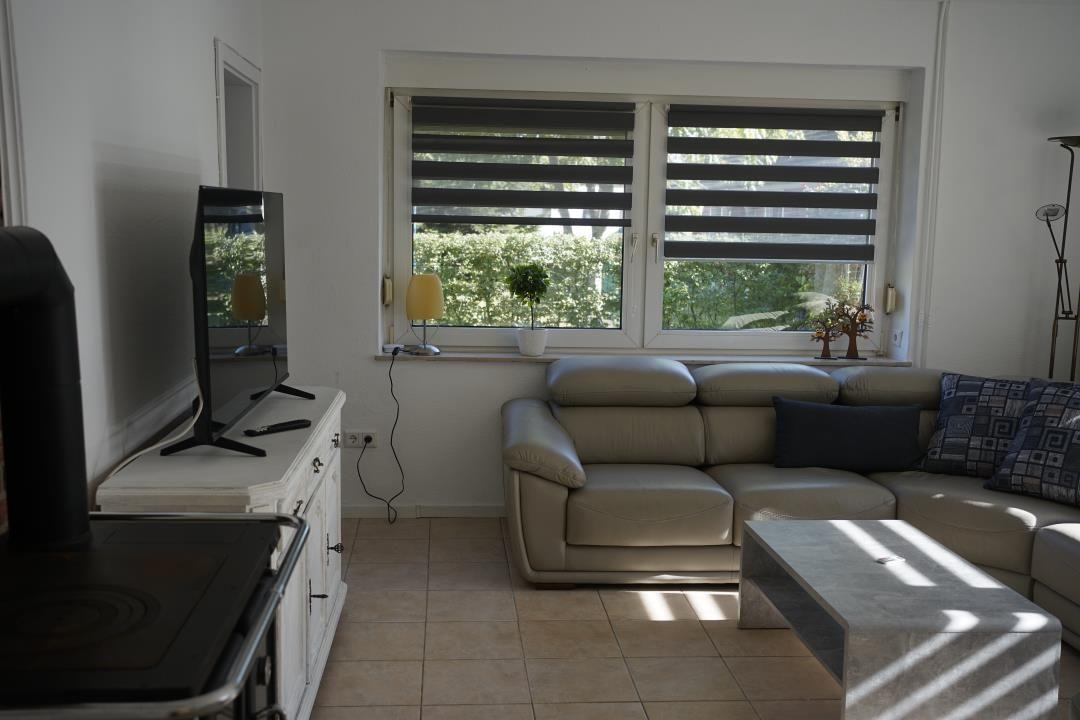 Living room with sofa, coffee table, and windows with blinds.