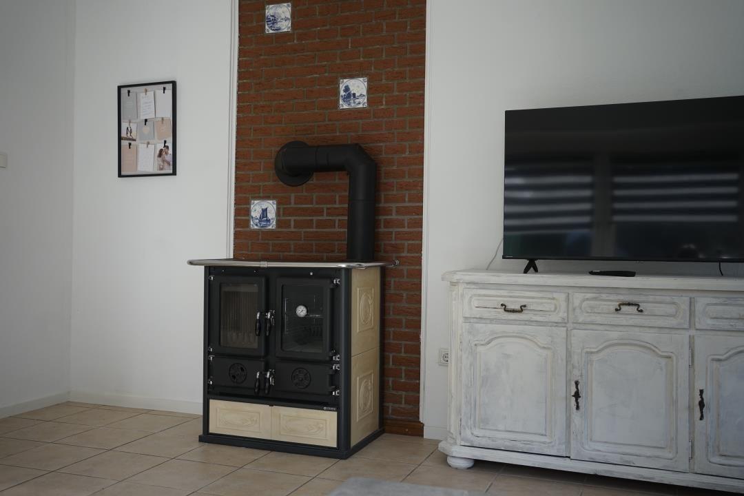 Stove against brick wall, TV on white cabinet