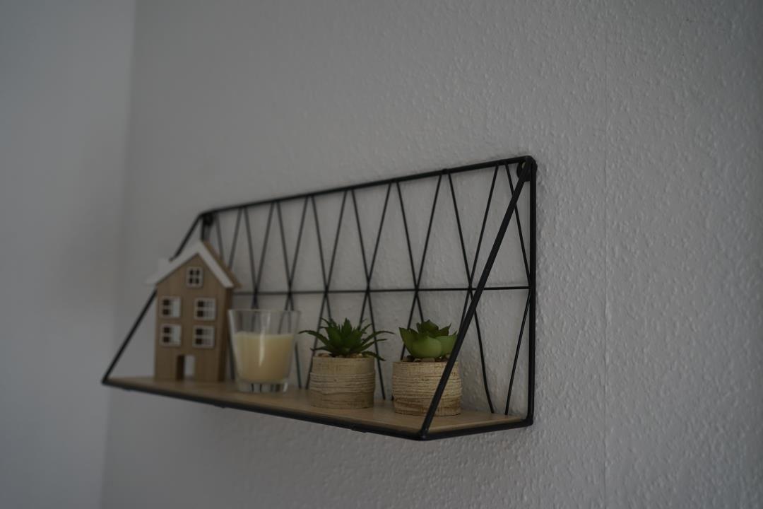 Wall shelf with small plants, candle, and house model on the wall